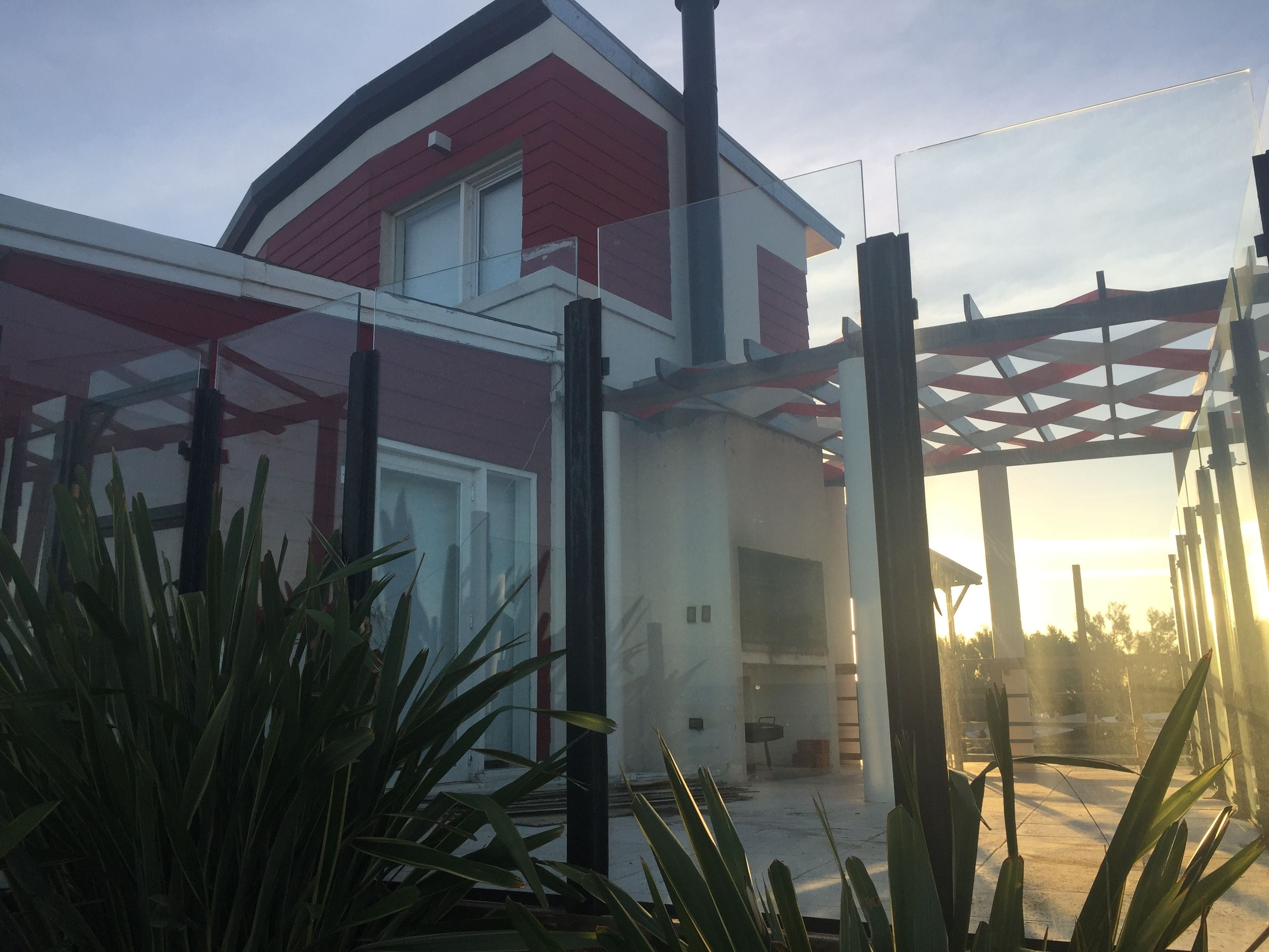 Ein modernes Haus mit rotem und weißem Anstrich, einer Glastür und einer Pergola.