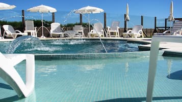 Una piscina techada, una piscina al aire libre de temporada, sombrillas