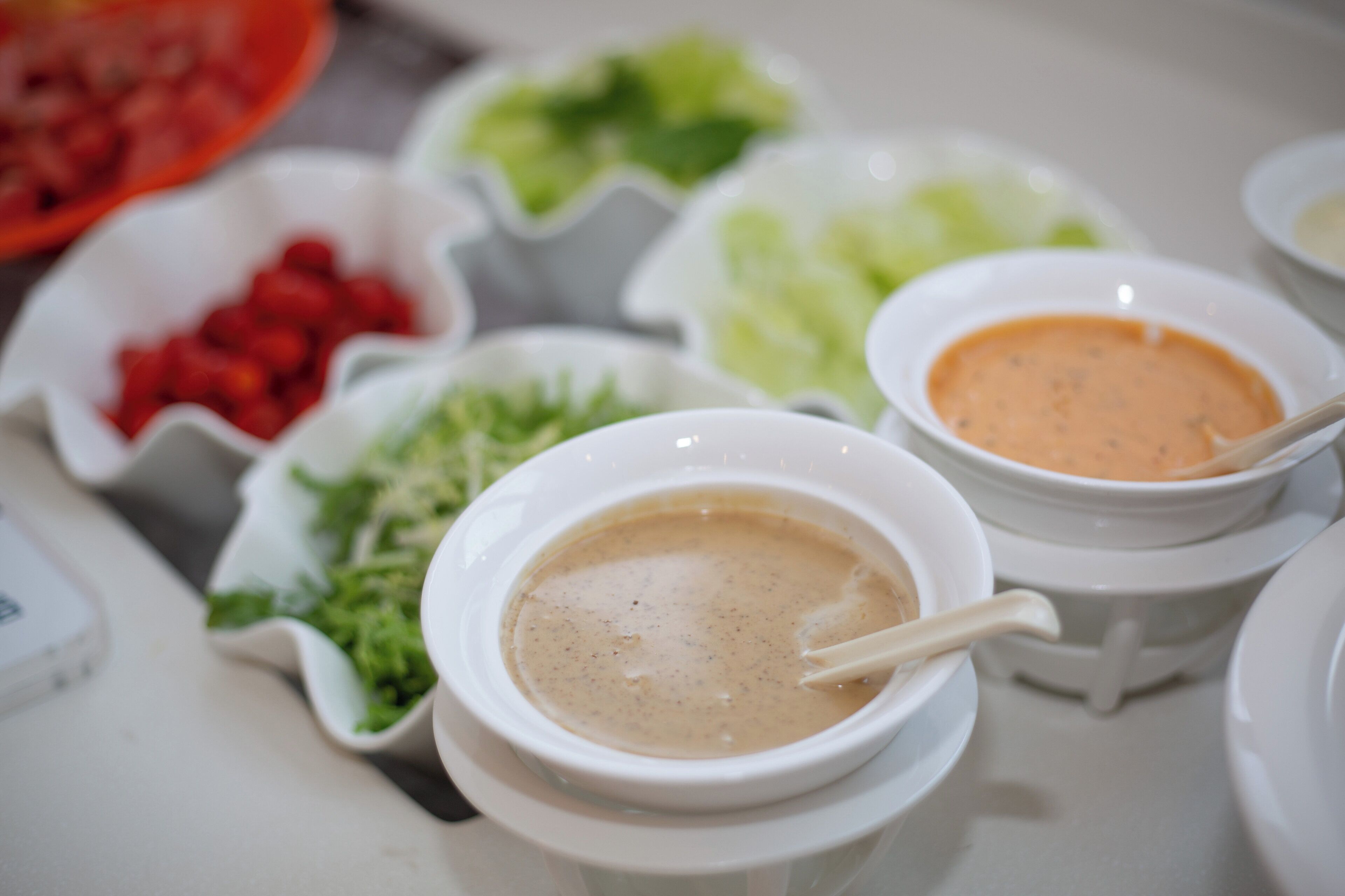 A variety of bowls containing different types of dips and sauces, arranged on a table.