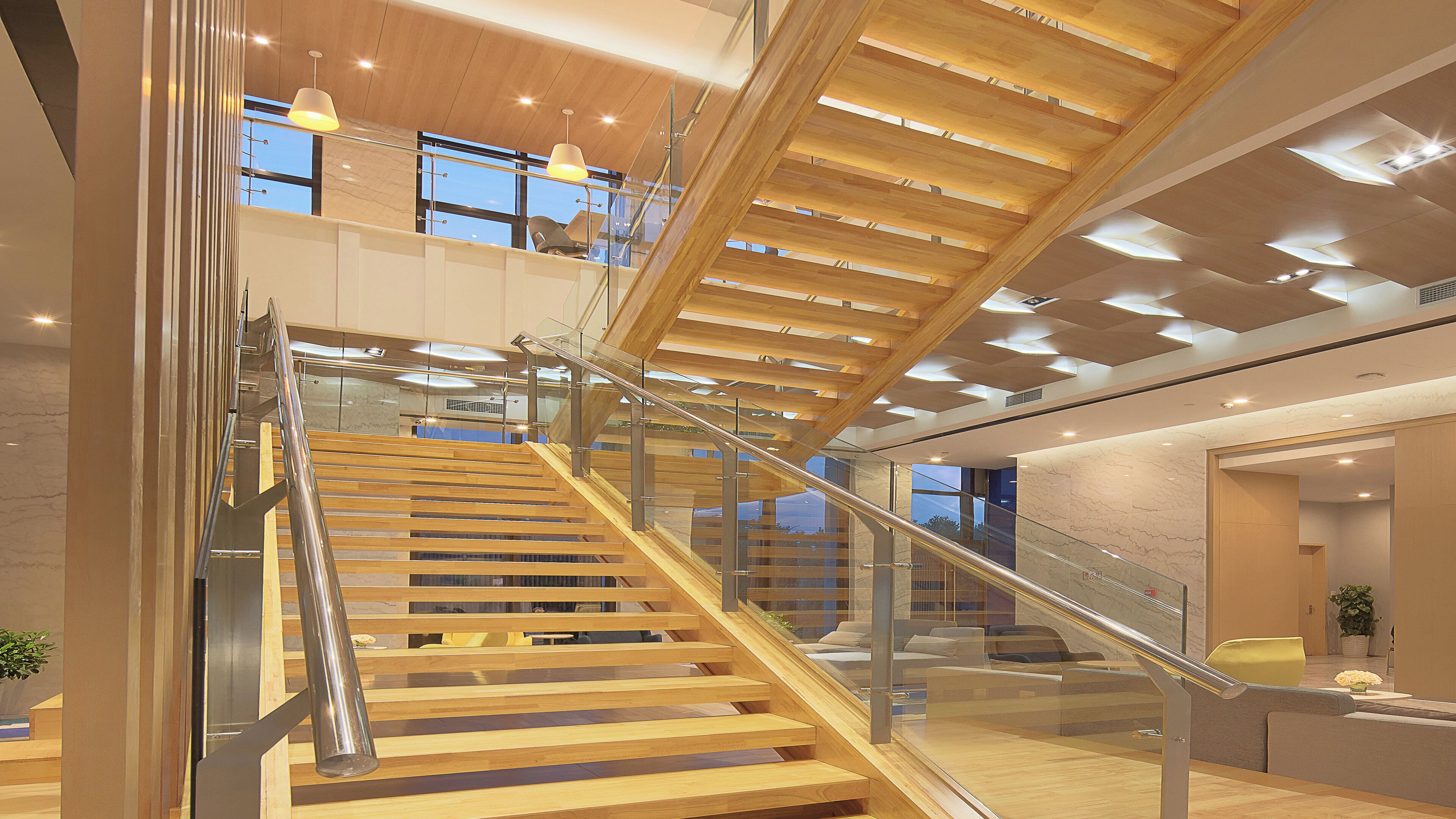 Ein modernes Interieur mit einer Holztreppe, Glastrennlärm und einer Decke mit integrierter Beleuchtung.