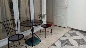 A small dining area with a round table and two chairs, a sliding glass door, and a tiled floor. - T-Rooms Homestay (Palembang)