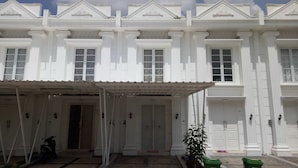 A white building with a covered entrance and a motorcycle parked outside. - T-Rooms Homestay (Palembang)