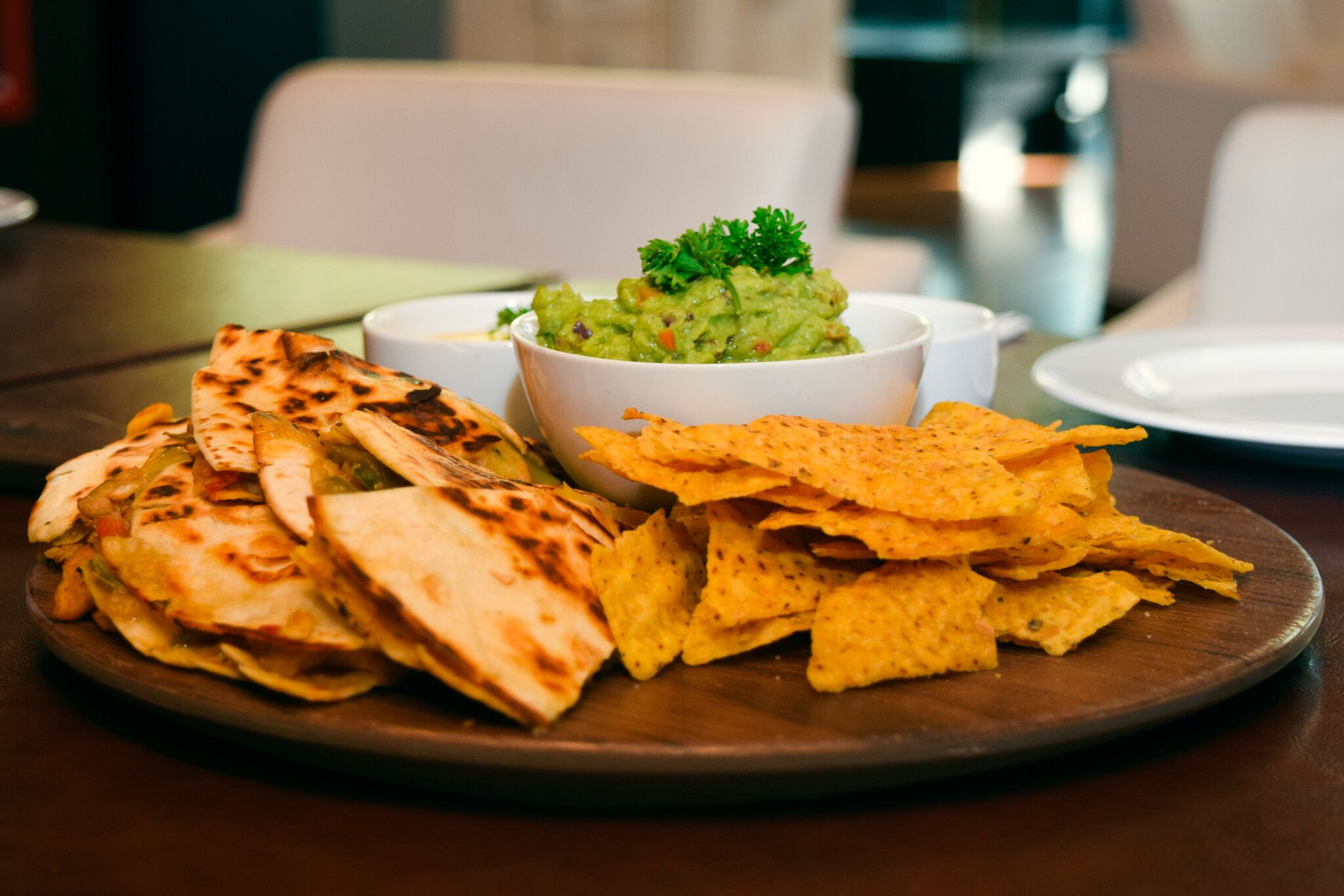 A plate of quesadillas and tortilla chips with a bowl of guacamole.