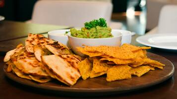 A plate of quesadillas and tortilla chips with a bowl of guacamole.