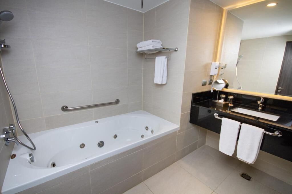 A modern bathroom with a bathtub, a vanity with a mirror, and a towel rack.