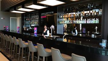 Zona de bar con una variedad de bebidas, una pizarra de menú y taburetes.