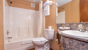 A bathroom with a bathtub, toilet, and sink. - Far West Motel (Forks)