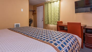 Una camera d'albergo con un letto grande, una scrivania, una sedia e una televisione appesa al muro.
