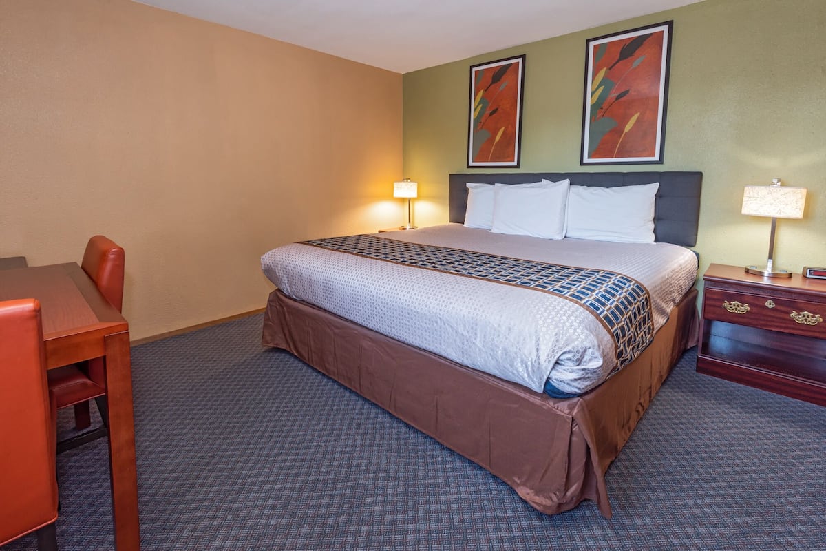 A hotel room with a bed, a desk, and two chairs.