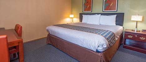 A hotel room with a bed, a desk, and two chairs.