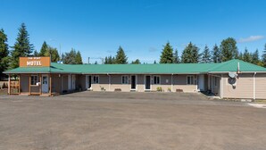 A motel with a green roof, multiple rooms, and a parking lot. - Far West Motel (Forks)