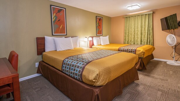 A hotel room with two beds, a desk, and a chair. - Far West Motel (Forks)