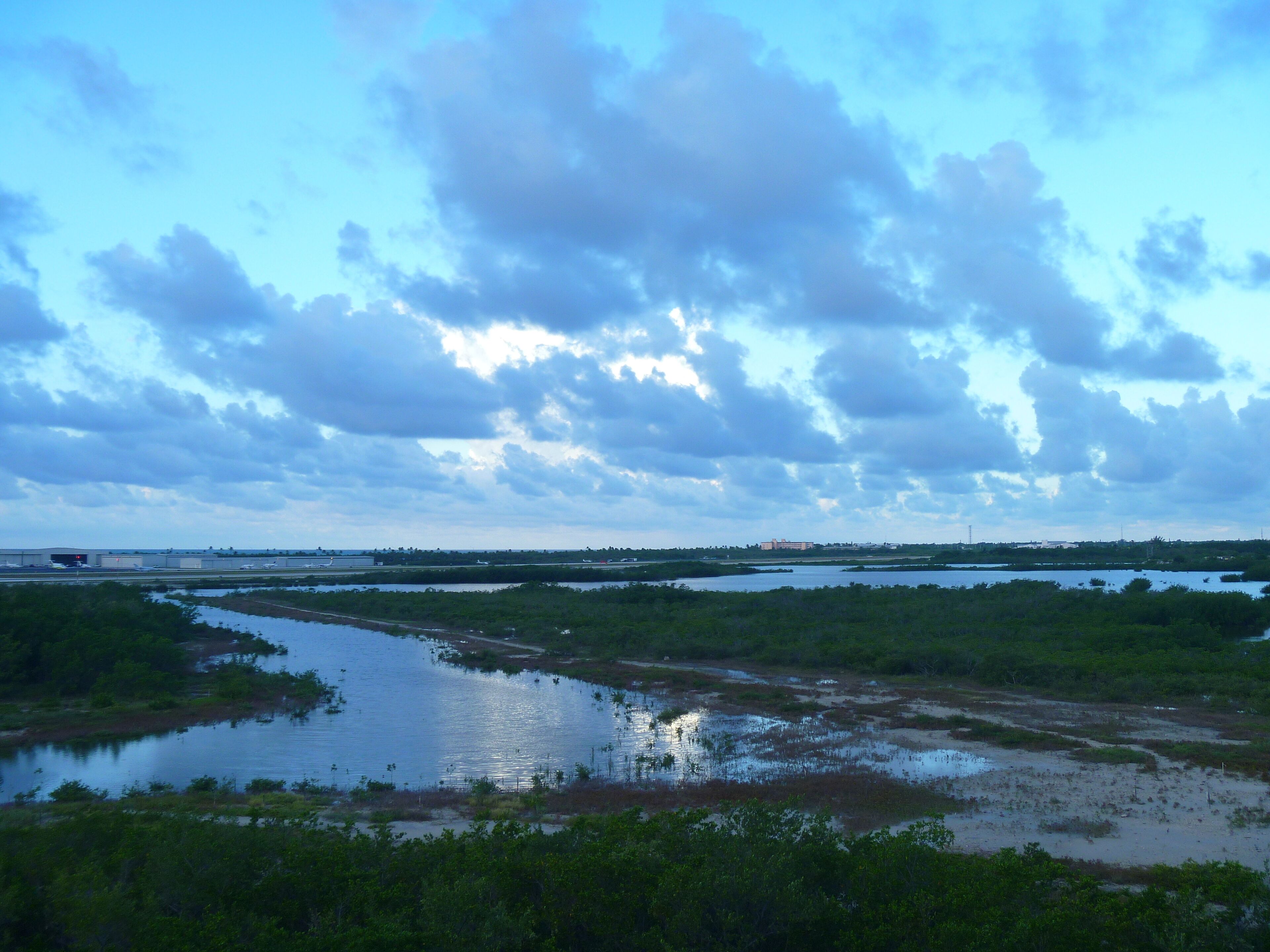 A landscape with a water body, vegetation, and a distant building.