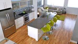 Una cocina moderna con una isla central, taburetes de bar, horno empotrado y refrigerador.