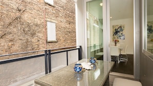 A modern room with a glass table, wicker furniture, and a brick wall. - Unique, contemporary 1,500ft2 2BR/2.5BA apt - OTR (Cincinnati)