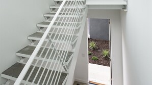 A modern staircase with white railings leading to an upper level. - Unique, contemporary 1,500ft2 2BR/2.5BA apt - OTR (Cincinnati)