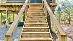 Eine hölzerne Treppe führt zu einem blauen Haus mit Tür und Fenstern.