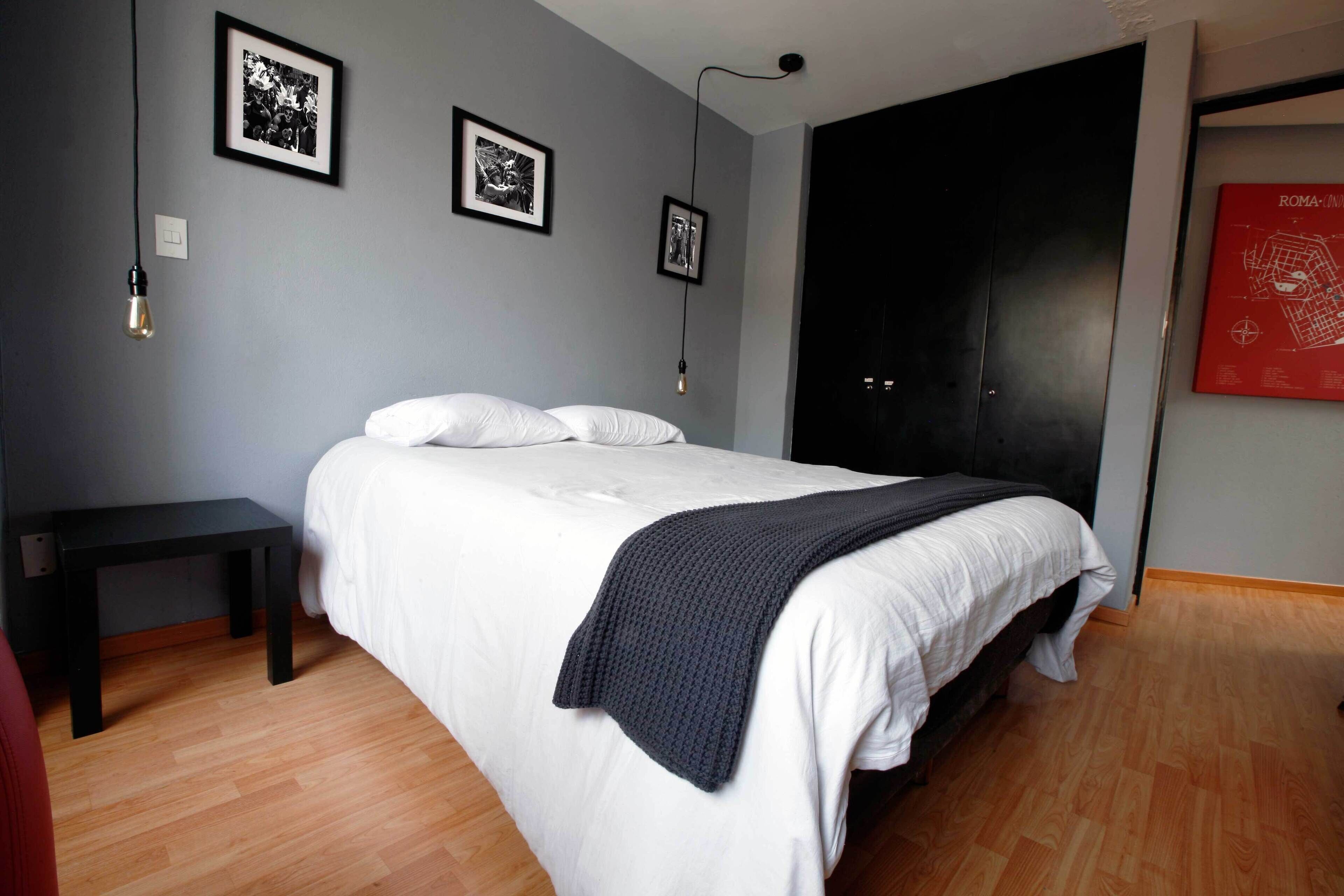 Une chambre à coucher avec un lit, une table de chevet et deux tableaux encadrés accrochés au mur.