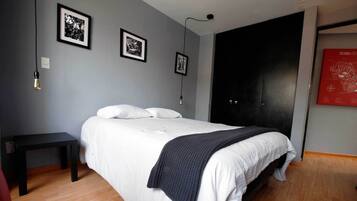 Une chambre à coucher avec un lit, une table de chevet et deux tableaux encadrés accrochés au mur.