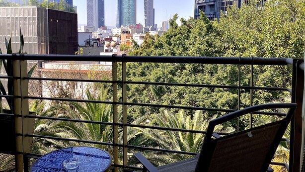 A balcony with a view of modern buildings and lush greenery. - Prime Roma Norte 2BR; Walk to Cibeles, Reforma & Condesa (México D.F.)