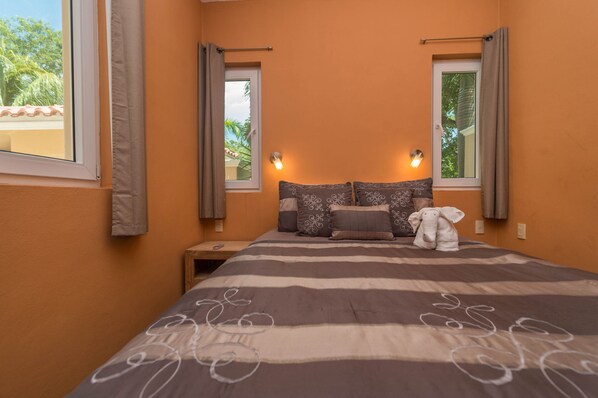 Une chambre à coucher avec une couvre-lit à rayures, deux lampes de chevet, une table de chevet et une fenêtre avec des rideaux.