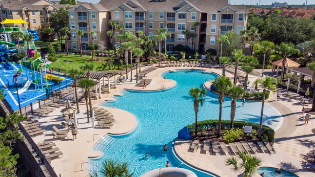 A resort with a large pool, water slides, and palm trees.