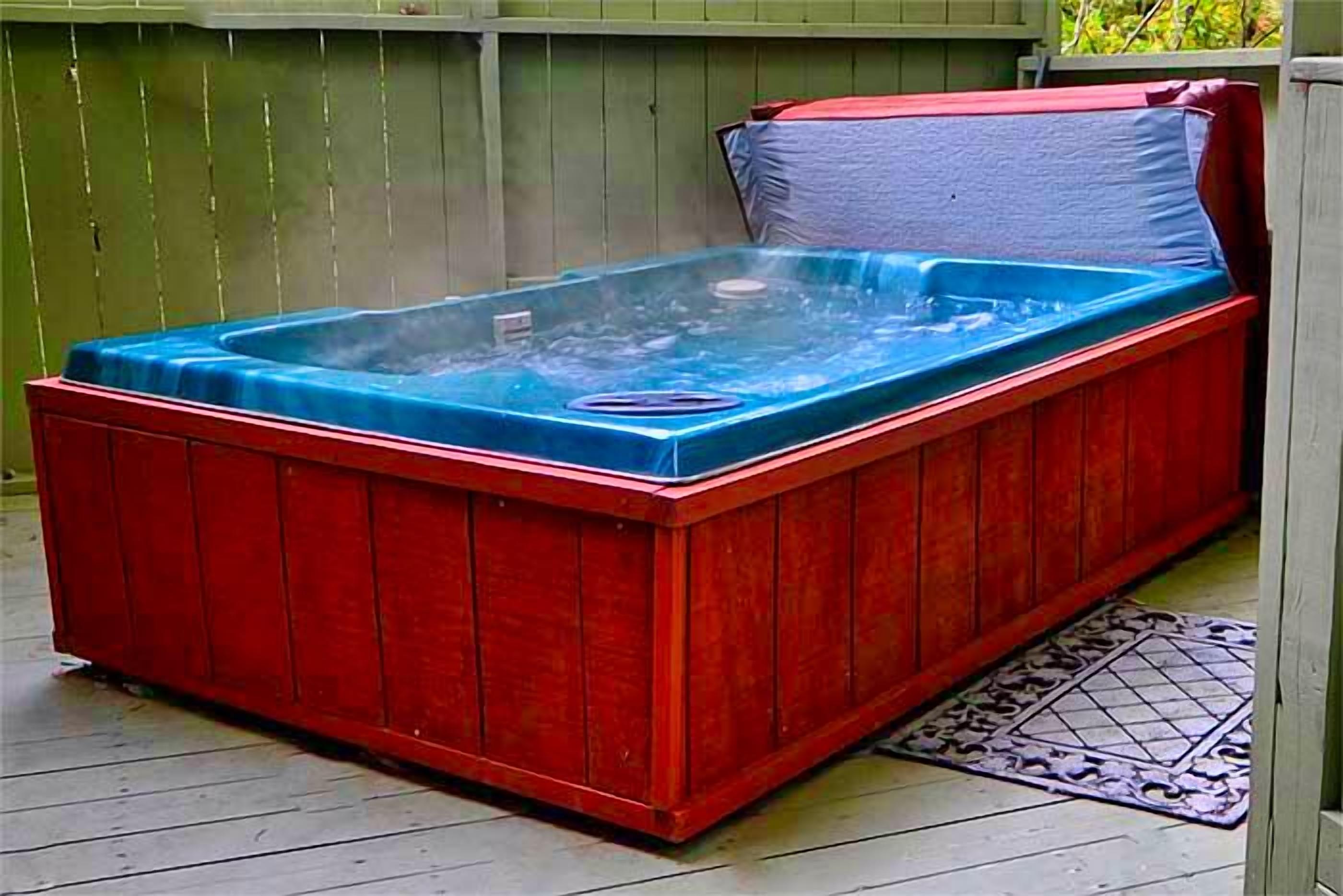 A hot tub with a blue cover, red exterior, and a wooden deck.