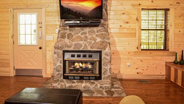 Una chimenea de piedra con un televisor encima, una puerta de madera y una ventana con persianas.