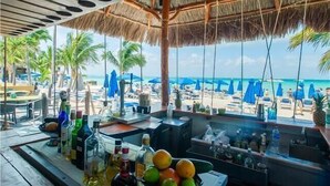 A bar with a view of a beach and palm trees. - Nautibeach Condo 22  – 2 Bedroom, Family-Friendly Vacation on the Beachfront Third-Floor (Isla Mujeres)