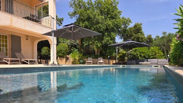 A clear swimming pool with lounge chairs and umbrellas, surrounded by greenery and a building with a balcony. - SUPERB VILLA (220m2), SEA AND VIEW BETWEEN ST MAXIME AND ISSAMBRES (Sainte-Maxime)