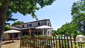 Una casa rustica con un recinto di legno, una piscina e un'area relax all'aperto.