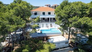 A two-story house with a swimming pool, surrounded by trees and RVs. - Beachfront apartment with Infinity Pool & BBQ (Slatine)