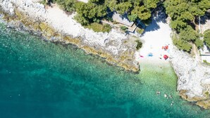 An aerial view of a coastal property with a swimming pool, a covered patio, and a large house with a red roof. - Beachfront apartment with Infinity Pool & BBQ (Slatine)