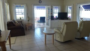 Un salón amplio con sofá, sillones, una mesita y televisión.
