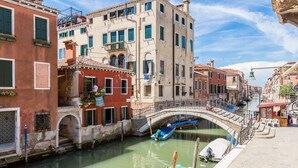 A canal with boats, a bridge, and buildings with balconies and windows. - Ca' Tintoretto (Venice)
