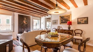 A dining area with a glass-top table, wooden chairs, a chandelier, and a red lamp. - Ca' Tintoretto (Venice)