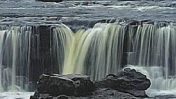 Waterfalls cascade over rocky terrain, creating a dynamic landscape.
