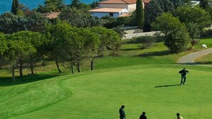 Un parcours de golf offrant une vue sur la mer et sur des maisons situées au loin.