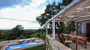 Un espace aménagé au bord de la piscine, doté d’une pergola, de sièges d’extérieur et offrant une vue sur le paysage.