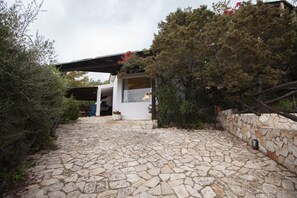 A stone-paved entrance to a modern building with a covered porch and a stone wall.