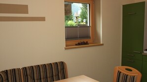 Ein Essbereich mit einem Tisch, einer gestreiften Couch, einem Fenster und einem grünen Schrank.