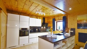 Une cuisine moderne avec des meubles blancs, un îlot central et un plafond en bois.