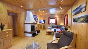 L’intérieur d’un chalet accueillant, avec des murs en bois, une cheminée, un canapé et un téléviseur.
