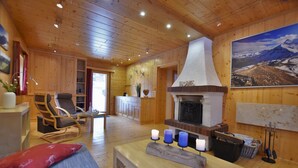Une pièce chaleureuse avec une cheminée, des meubles en bois et une vue sur les montagnes.