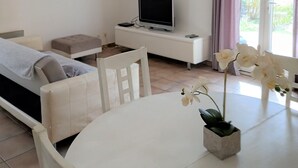A modern living room with a sofa, a TV, a dining table, and a chandelier. - On the edge of a forest, in green Provence, with private swimming pool (Brignoles)
