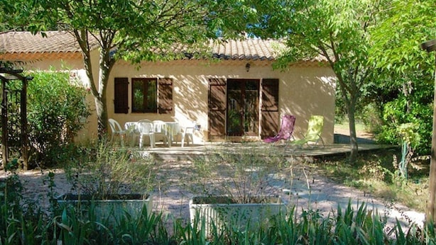 A house with a tiled roof, a porch with plastic chairs, and a garden area with plants. - On the edge of a forest, in green Provence, with private swimming pool (Brignoles)