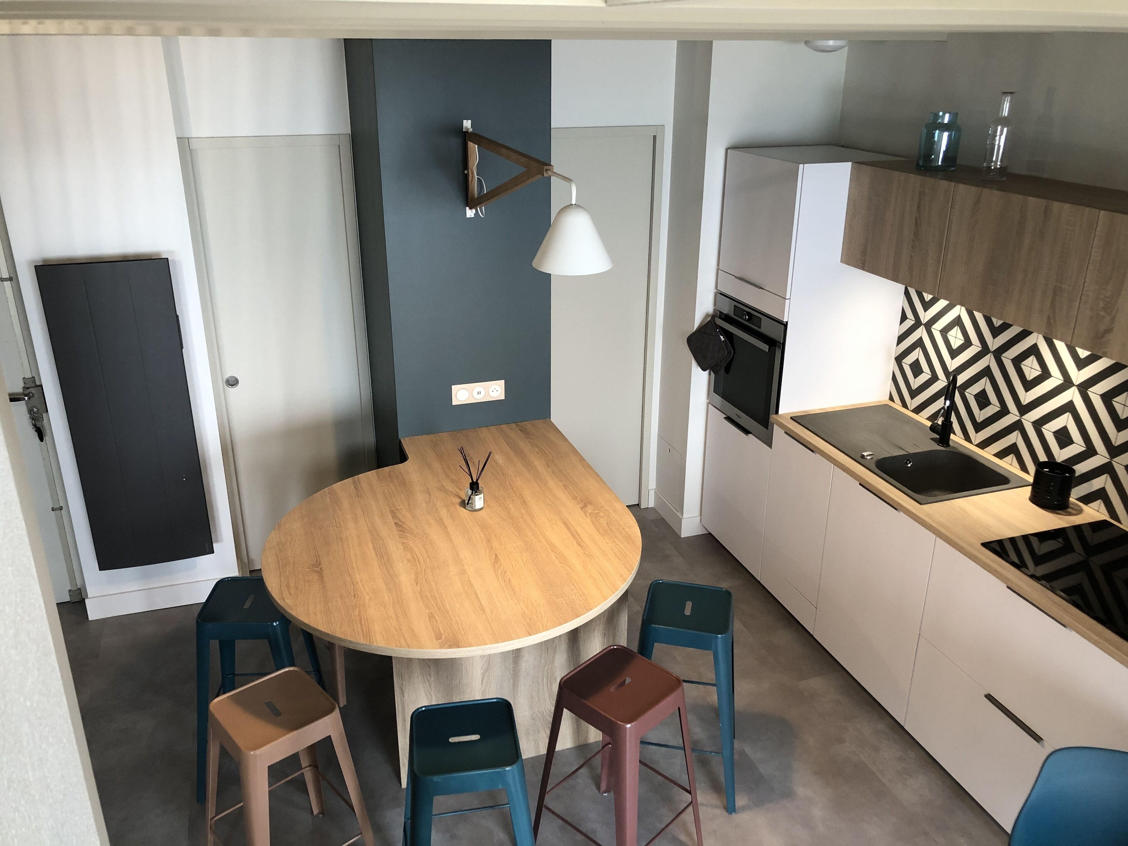 Una cucina compatta con un tavolo rotondo in legno, quattro sgabelli, un forno integrato e uno schienale decorato.