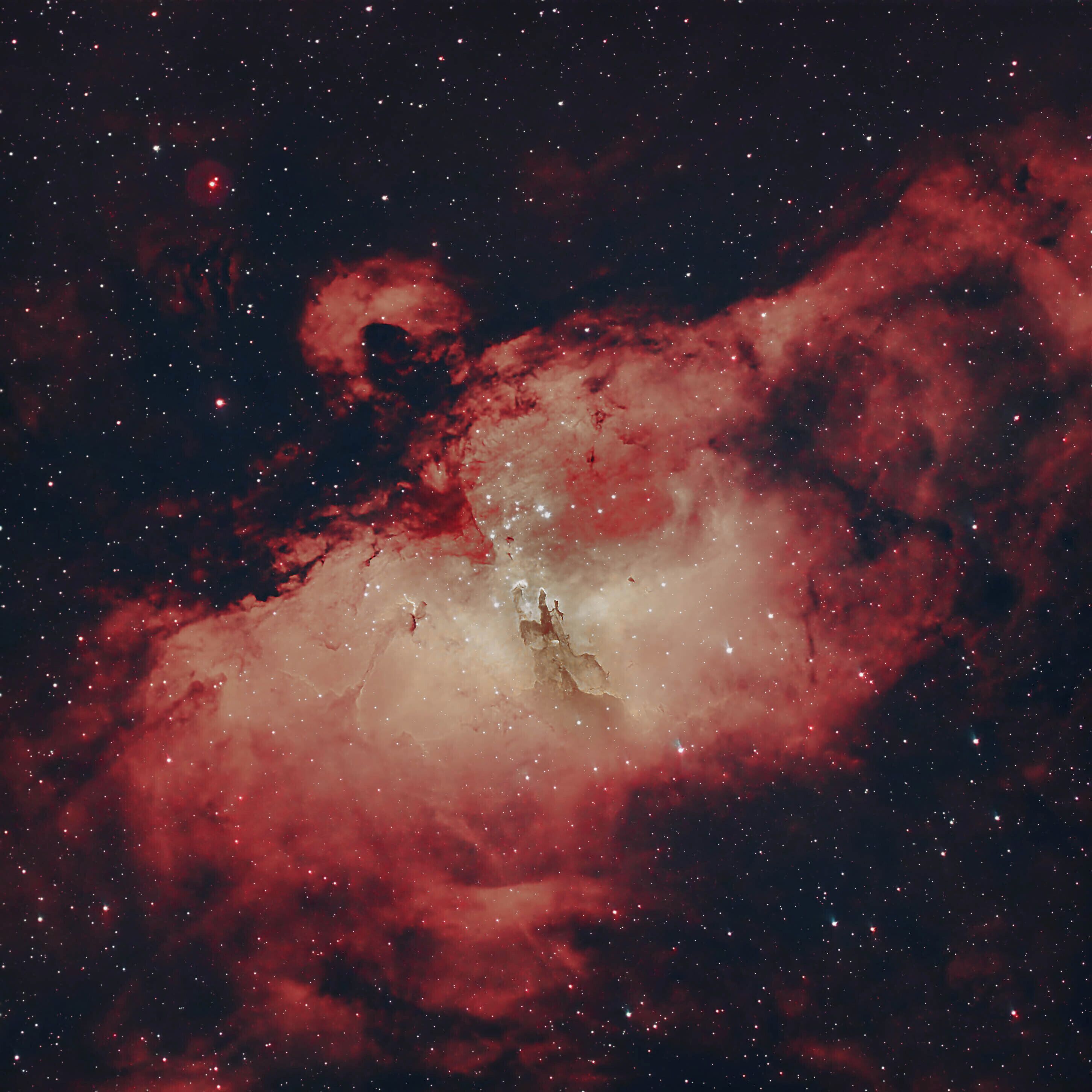 Una nebulosa con un área central brillante y nubes rojas circundantes.