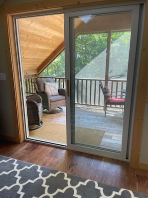 Une terrasse en bois avec des meubles en osier et une chaise rouge.