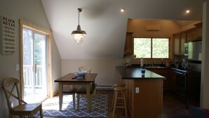 Een keuken met een houten keukeneiland, een eettafel met stoelen en een hanglamp.